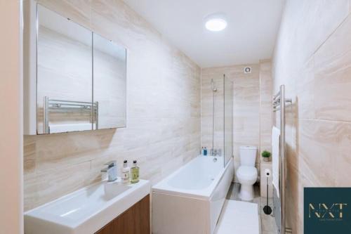 Apartment in Central Watford في واتفورد: حمام مع حوض ومرحاض ومرآة