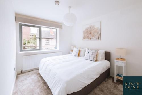 Apartment in Central Watford في واتفورد: غرفة نوم بيضاء مع سرير أبيض كبير ونافذة