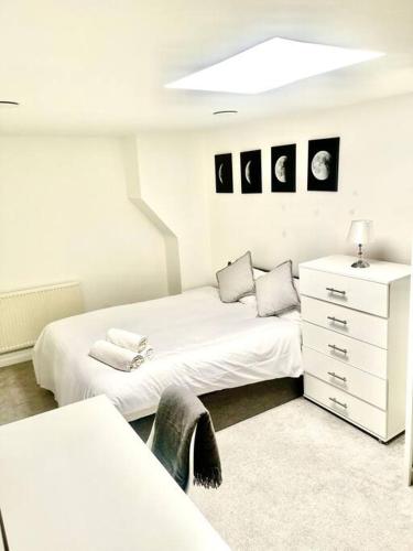 a white bedroom with two beds and a dresser at Lovely one bed Fitzrovia/soho in London