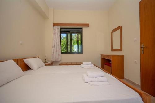 1 dormitorio con 1 cama blanca grande y toallas. en Xenios Zeus Apartments en Kíssamos