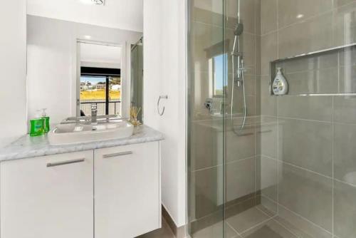 a bathroom with a glass shower and a sink at Castaway Views on Broadway in San Remo