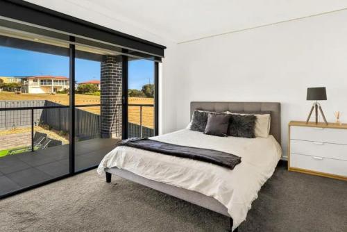 a bedroom with a large bed and a balcony at Castaway Views on Broadway in San Remo