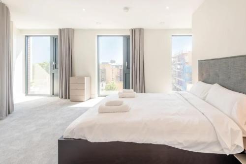 ein weißes Schlafzimmer mit einem großen Bett und großen Fenstern in der Unterkunft Modern Apartments in Brentford 2 minutes walk from Kew Bridge in Brentford