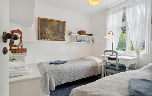 a bedroom with two beds and a desk and a window at 2 Bedroom Pet Friendly Apartment In Svaneke in Svaneke