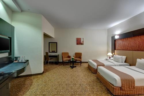 una camera d'albergo con 2 letti e una scrivania di Aryana Hotel a Sharjah
