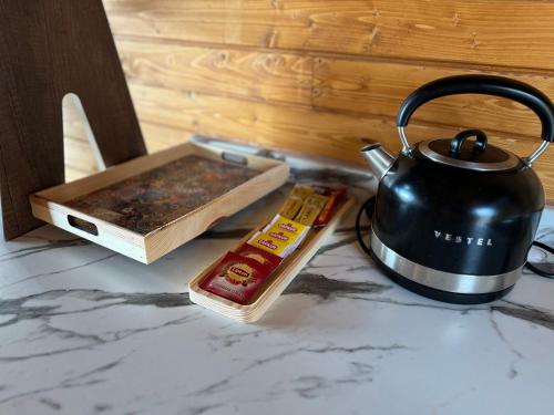 a tea kettle and a book on a counter at Defne Bungalow Yomra in Yomra