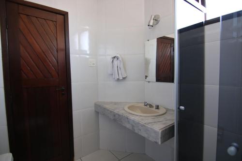 ein Badezimmer mit einem Waschbecken und einer Holztür in der Unterkunft Samba Betim in Betim