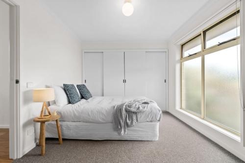 a white bedroom with a bed and a window at Cloud Nine - Centre of town, walk everywhere in Apollo Bay