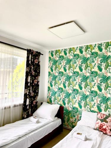 2 łóżka w pokoju z tropikalnymi tapetami w obiekcie Happy Living Hostel we Wrocławiu