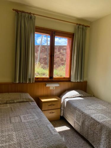 a bedroom with two beds and a window at Hostal Alt Llobregat in Castellar de NʼHug