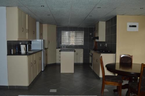 a kitchen with white cabinets and a table in it at Prison View Guesthouse 1 in Klerksdorp