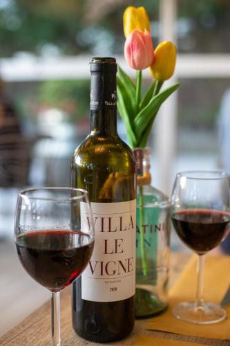 a bottle of wine next to two glasses of red wine at Agriturismo Villa Le Vigne in Montevarchi