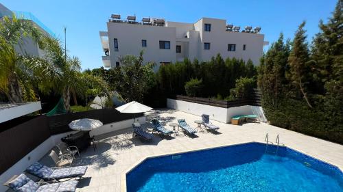 a swimming pool with chairs and a building at Villa Sawa by Ezoria Villas in Limassol