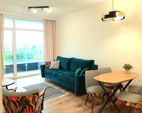 uma sala de estar com um sofá azul e uma mesa em Apartament Tropikalny prywatny taras na dachu z widokiem na morze em Sianozety