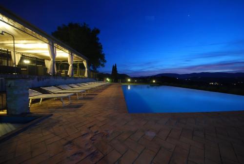 a row of benches sitting next to a pool at night at Spoleto by the pool in Spoleto
