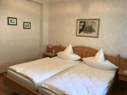 a bedroom with a bed with white sheets and pillows at Pension / Ferienwohnung Allebrodt in Lennestadt