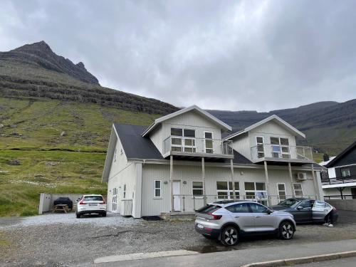 a house with two cars parked in a parking lot at Lokk-Inn Apartments in Norðdepil