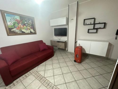 un soggiorno con divano rosso e TV di Casa vacanze a Scoglitti