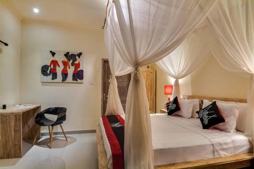 ein Schlafzimmer mit einem Himmelbett und einem Stuhl in der Unterkunft Selog Villa 2 in Seminyak