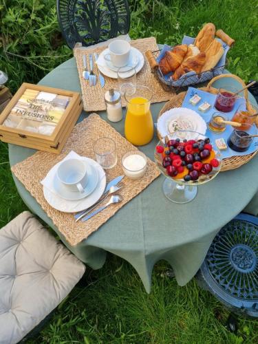 a picnic table with plates of food and a bowl of fruit at ENTRE VENTOUX ET LUBERON Chambre d'hôte in Sault-de-Vaucluse