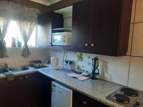 eine Küche mit schwarzen Schränken und einer Arbeitsplatte in der Unterkunft Aviators Retreat B&B in Krugersdorp