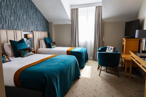 a hotel room with two beds and a desk at Lahinch Coast Hotel and Suites in Lahinch