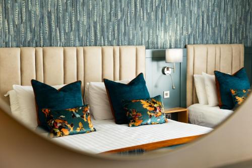 a bedroom with a bed with blue pillows at Lahinch Coast Hotel and Suites in Lahinch