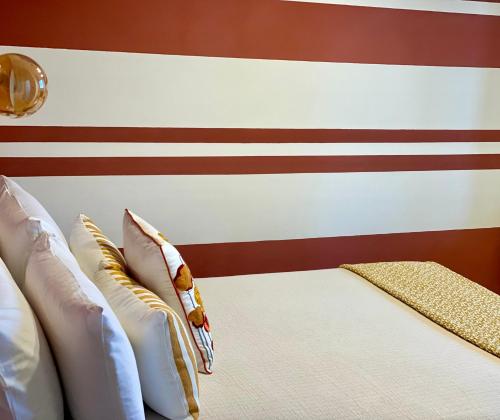 a bed with pillows and a red and white stripe wall at HABITARE Lecce & Salento in Lecce