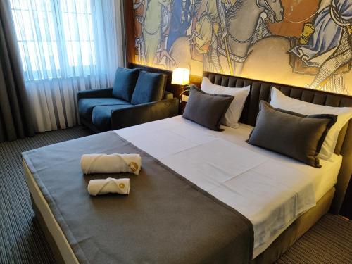 um quarto de hotel com uma cama grande e uma cadeira em Orienta Hotel Gyumri em Guiumri