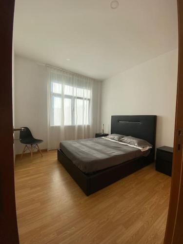 een slaapkamer met een bed en een stoel op een houten vloer bij Apartamento em braga in Braga