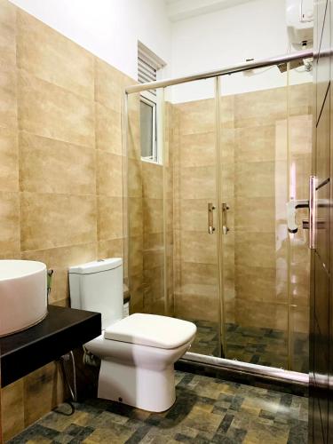 a bathroom with a toilet and a glass shower at Villa Avi - Near Airport in Negombo