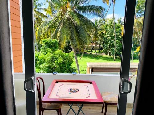 a table and chairs on a balcony with a palm tree at Villa Avi - Near Airport in Negombo