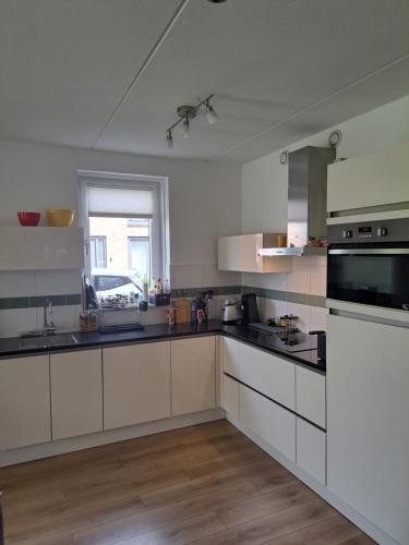 a large kitchen with white cabinets and a window at Dubbelink 3A in Amsterdam