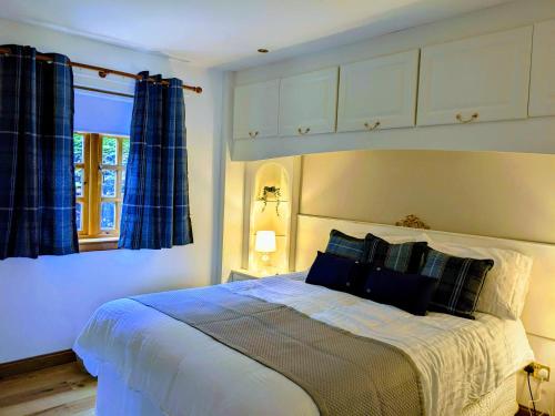 a bedroom with a large bed with blue curtains at Heather Cottage Luss in Luss