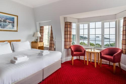 um quarto de hotel com uma cama, uma mesa e cadeiras em The Headland Hotel & Spa em Torquay