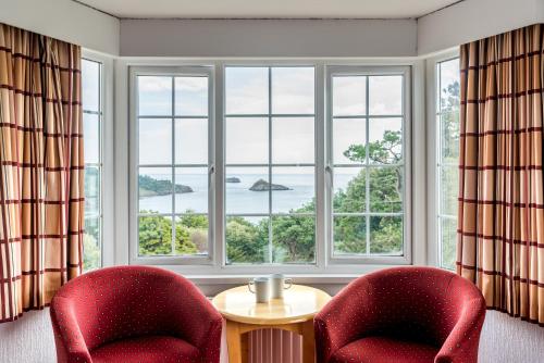 two red chairs and a table in front of a window at The Headland Hotel & Spa in Torquay