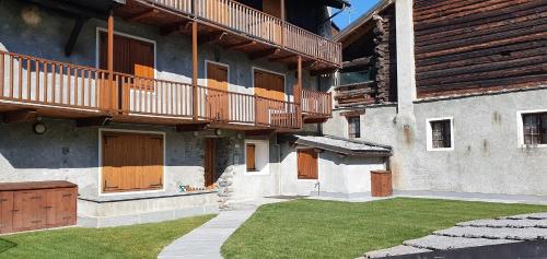 a building with wooden doors and a grass yard at Il Rifugio di Marcella in Challand Saint Anselme