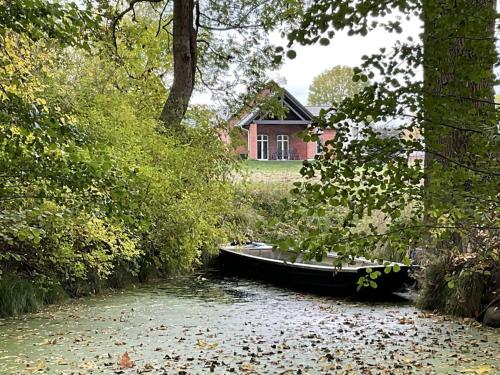 un barco en un río frente a una casa en Ferienhaus Spreewaldhof am Wasser "Das Landhaus", en Raddusch