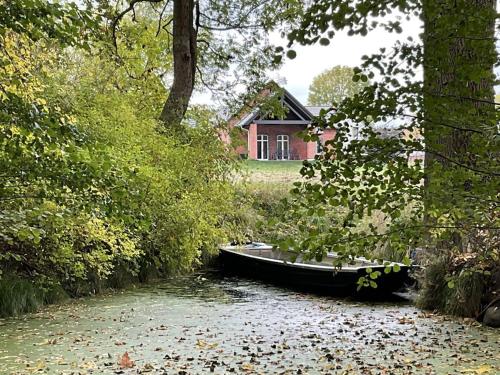 ein Boot auf einem Fluss vor einem Haus in der Unterkunft Ferienhaus Spreewaldhof am Wasser "Das Landhaus" in Raddusch