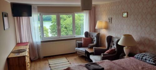フミエルノにあるSKOLIMÓWKAのベッド1台、椅子2脚、窓が備わる客室です。