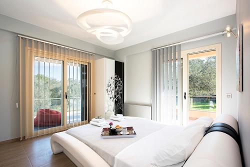 ein weißes Schlafzimmer mit einem großen Bett und einem großen Fenster in der Unterkunft Contemporary Corfu Retreat - 3 Bedrooms - Villa Girasole - Artful Decor - Lush Garden - Tranquil Setting in Dafnila