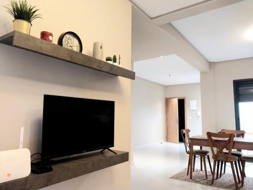 a living room with a tv and a table with chairs at Cosy appartement proche de l'aéroport mohamed 5 in Deroua