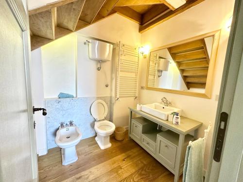 een badkamer met een wastafel, een toilet en een spiegel bij Incredible experience in an ancient Convent from the 1200s in Ginestra