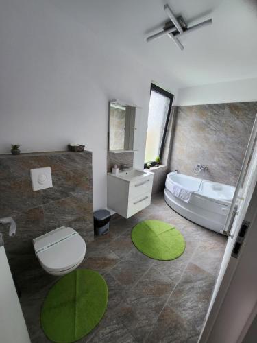 a bathroom with a white tub and a green rug at Armins's Residence 2 - Villa in Dumbrăviţa