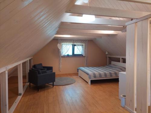 a bedroom with a bed and a chair in a attic at MI namiņš in Robežnīca