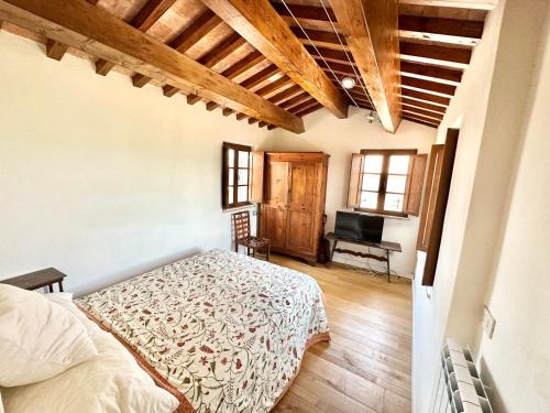 een slaapkamer met een bed en een bureau met een televisie bij Incredible experience in an ancient Convent from the 1200s in Ginestra