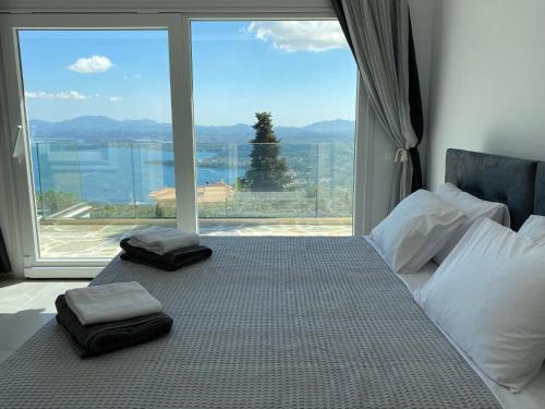 a bed with two towels on it with a large window at RIZARIA sea view house in Spartýlas