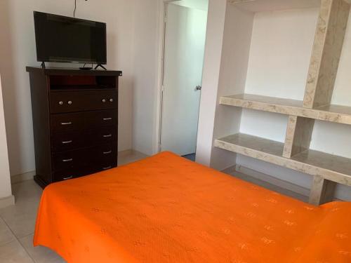 - une chambre avec un lit et une commode avec une télévision dans l'établissement Apto en Flandes Tolima., à Flandes