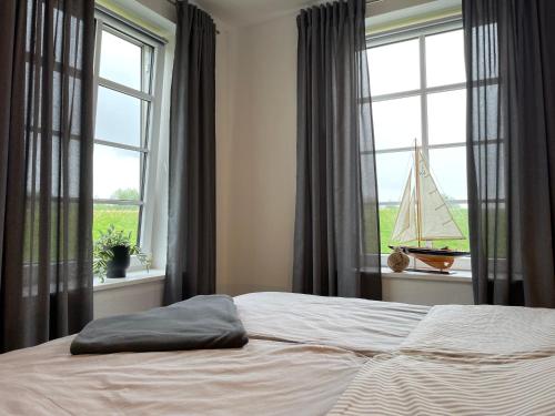um quarto com uma cama e janelas com um veleiro na janela em Deichperle Krautsand em Drochtersen