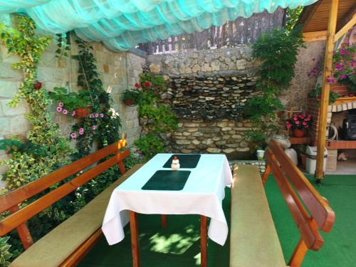 una mesa y dos bancos en una habitación con flores en Guest House Stoletnika, en Yagodina